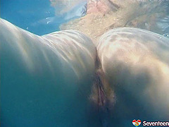 Skinny dipping teens play in the pool and finger underwater